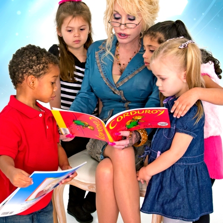 Dolly Parton sits and reads a book to children gathered around her